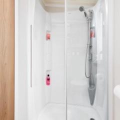 a shower in a bathroom with red buttons on the wall at Presthaven Sands Holiday Park 3 and 2 Bed Caravans in Prestatyn