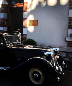 un viejo coche negro estacionado frente a un edificio en Le 1930, chambres d’hôtes de charme en Cosne Cours sur Loire