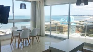 sala de estar con mesa, sillas y ventana grande en Blaumer Apartamentos - Edificio Aguila Dorada, en Punta del Este