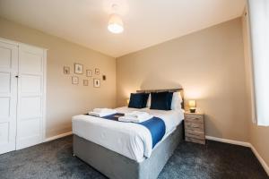 een slaapkamer met een groot bed met blauwe kussens bij Wolviston House By Horizon Stays in Stockton-on-Tees