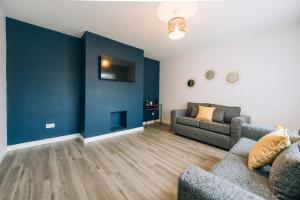 una sala de estar con 2 sofás y una pared azul en Wolviston House By Horizon Stays, en Stockton-on-Tees
