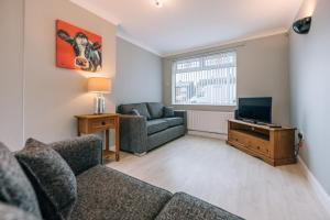 a living room with a couch and a tv at Dinsdale House By Horizon Stays in Stockton-on-Tees