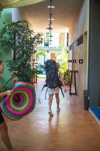 Hostik Hostal في ميريدا: شخص لديه حقيبة ظهر يمشي في الردهة مع النباتات