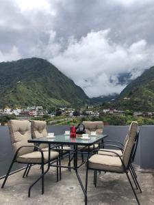 einen Tisch und Stühle auf einem Balkon mit Bergblick in der Unterkunft Penthouse w/rooftop terrace - volcano view in Baños