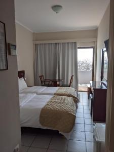 a bedroom with a bed and a table and a window at LEPANTO BEACH HOTEL in Nafpaktos