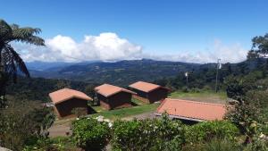 a group of huts with mountains in the background at Hotel Mirador de Quetzales in Providencia