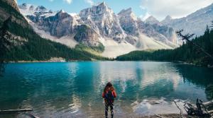 a woman standing in front of a lake with mountains at Chic Studio Minutes to DT in Calgary