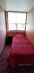 a small bedroom with a red bed with a window at Dpto frente a Cavancha 6P in Iquique