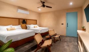 a hotel room with two beds and two chairs at Bacalari Hotel Boutique in Bacalar