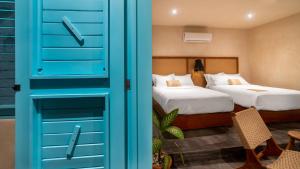 a room with two beds and a blue door at Bacalari Hotel Boutique in Bacalar