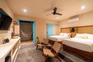 a hotel room with two beds and a flat screen tv at Bacalari - Adults Only in Bacalar