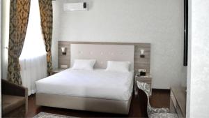 1 dormitorio con cama blanca y ventana en Reikartz Sunkar Atyrau, en Atyraū