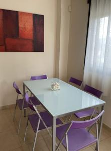 a table with purple chairs in a room with a painting at Residencial Los Flamencos in Benicàssim