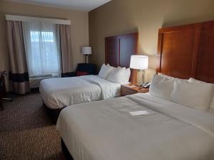 una camera d'albergo con due letti e una finestra di Wingate by Wyndham Pittsburgh New Stanton a New Stanton