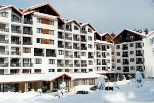 a large apartment building with snow in front of it at Апартамент B9 in Borovets