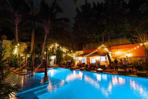 una piscina notturna con persone sedute intorno di Che Nomadas Mérida Hostel Adults Only a Mérida