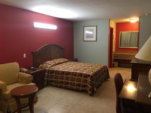 a hotel room with a bed and a chair at Texas Inn in Brownsville