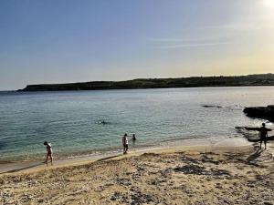 a group of people walking on the beach at Cute Penthouse in Marsaskala