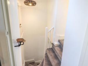 a hallway with a staircase with a light fixture at Violet Cottage in Ambleside