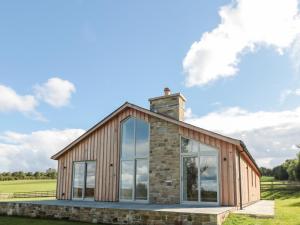 ein Holzhaus mit einem gemauerten Kamin und großen Fenstern in der Unterkunft Clover Cottage in Newcastle upon Tyne