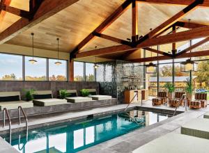 an indoor swimming pool with a patio and a house at Wildflower Farms, Auberge Resorts Collection in Gardiner