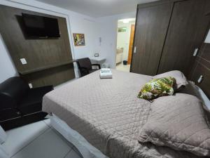 1 dormitorio con 1 cama con silla y TV en Israel Flat da Mar & Sol, en João Pessoa