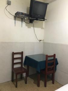 Habitación con mesa, 2 sillas y TV. en Hotel Luque, en Guayaquil