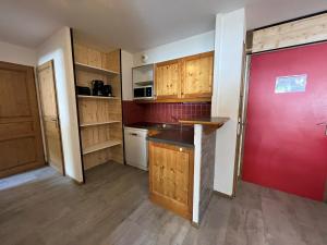 a kitchen with wooden cabinets and a red door at Appartement Lanslevillard, 3 pièces, 6 personnes - FR-1-508-26 in Lanslevillard