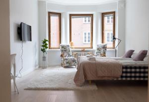 a white living room with a bed and two chairs at 2ndhomes Luxurious 144 m2 Stylish 3 Bedroom Center Apartment in Helsinki