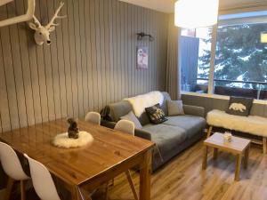 ein Wohnzimmer mit einem Tisch und einem Sofa in der Unterkunft Charmant studio cabine COCOON à 100 m des pistes in Chamrousse