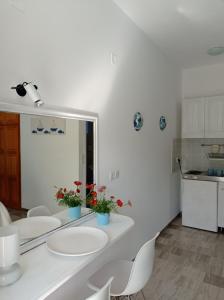 a white kitchen with white chairs and a mirror at Poseidon Studios Eressos in Skala Eresou