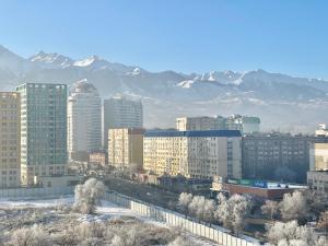 una ciudad con edificios y montañas en el fondo en Шикарные апартаменты с прекрасным видом в лучшем районе, en Almaty