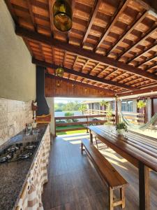 una cocina con techos de madera y una mesa con bancos. en Pousada Luz de Candeia, en São João Batista do Glória