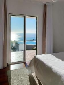 a bedroom with a bed and a view of the ocean at Neves by BCA Villas in São Gonçalo