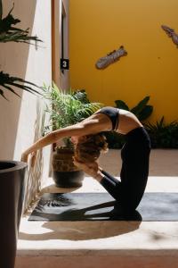 uma mulher a fazer uma pose de yoga em frente a algumas plantas em Hostik Hostal em Mérida