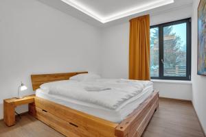 a bedroom with a large bed and a window at SCANDIC Apartments Plešivec in Abertamy