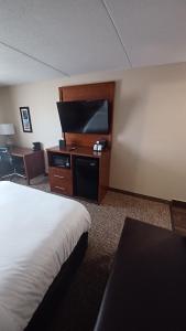 a hotel room with a bed and a flat screen tv at Wingate by Wyndham Pittsburgh New Stanton in New Stanton