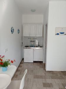 a small kitchen with white cabinets and a table at Poseidon Studios Eressos in Skala Eresou