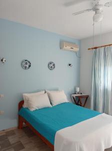 a bedroom with a bed with blue and white sheets at Poseidon Studios Eressos in Skala Eresou