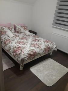 a bedroom with a bed with a floral blanket and a rug at Apartment Studenac in Pale