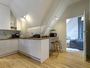 uma cozinha com armários brancos e uma cama num quarto em VisitZakopane- Toscana Apartment em Zakopane