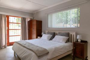 a bedroom with a large white bed with a window at The Jbaynian Guesthouse in Jeffreys Bay