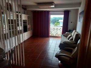 een woonkamer met een bank en een raam bij Albufeira INN - Casa dos Aveiros - Dolamar 4A T1 in Albufeira