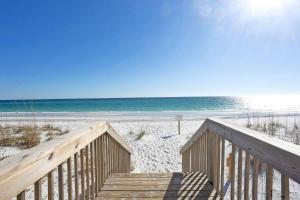 a wooden staircase leading to a beach with the ocean at Pensacola Beach Front Emerald Waters in Pensacola Beach