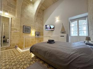 a bedroom with a bed and a tv on a wall at Capital City Apartment in Valletta