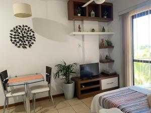 a bedroom with a bed and a table and a television at Apartamento no Rio Vermelho - Bairro Boêmio de Salvador in Salvador