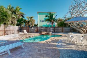 un patio trasero con piscina con banco y sombrilla en Sea's The Day, en Anna Maria