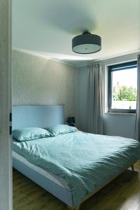 a bedroom with a bed with a blue comforter and a window at Hortensja in Wilków