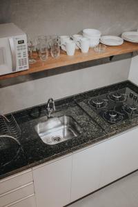 eine Küchentheke mit einer Spüle und einer Mikrowelle in der Unterkunft Pousada Refúgio do Vale - Praia do Rosa in Praia do Rosa
