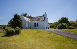 a white cottage on a grassy hill at Ploughman's Cottage in Edinbain